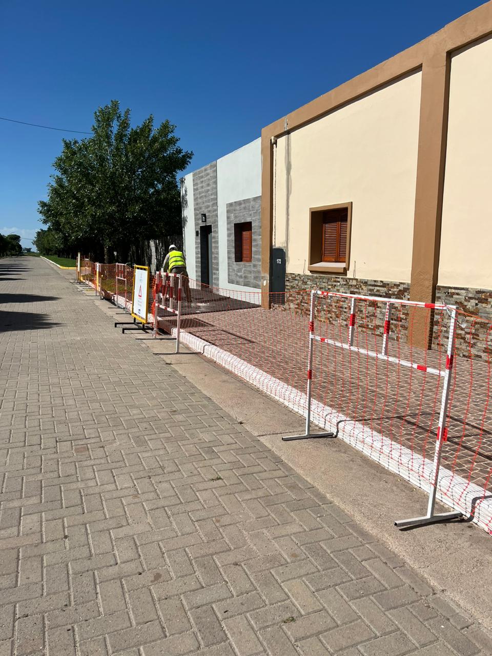 Vista de obra en calle con operario y vallado
